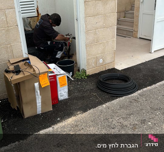 אדם עובד על צינור מים עם כלי עבודה